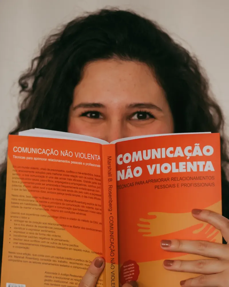 Julia Kalil espiando por cima do livro Comunicação Não Violenta